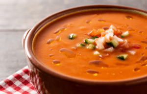 Gazpacho soup garnished with diced vegetables and fresh herbs, served chilled.